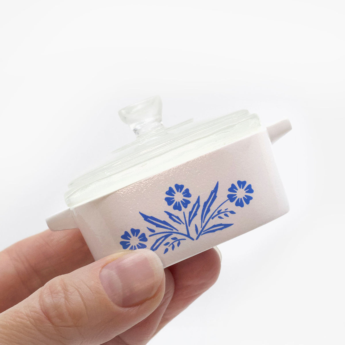 Mini trinket box held with clear lid, blue cornflower stem pattern on side