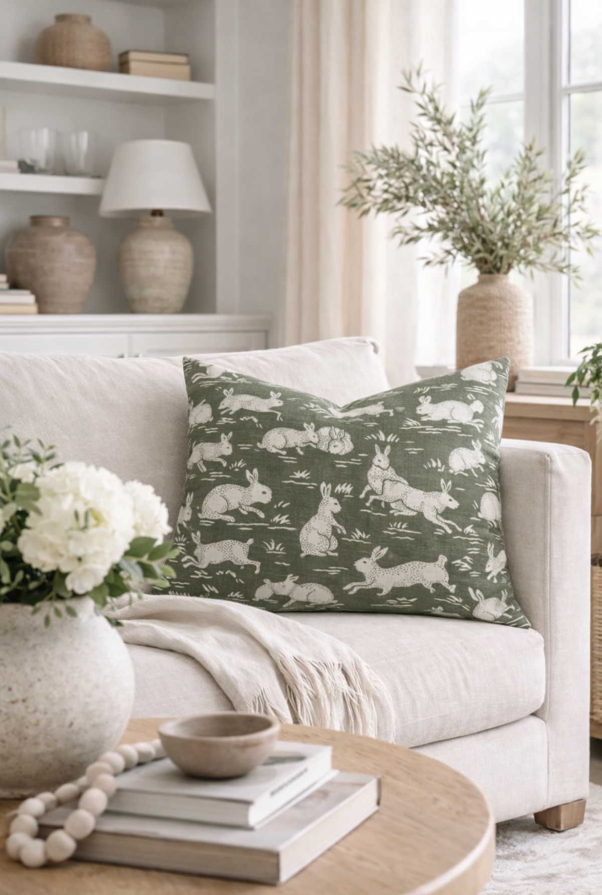 Sage green cotton pillow cover with white rabbit pattern on a sofa