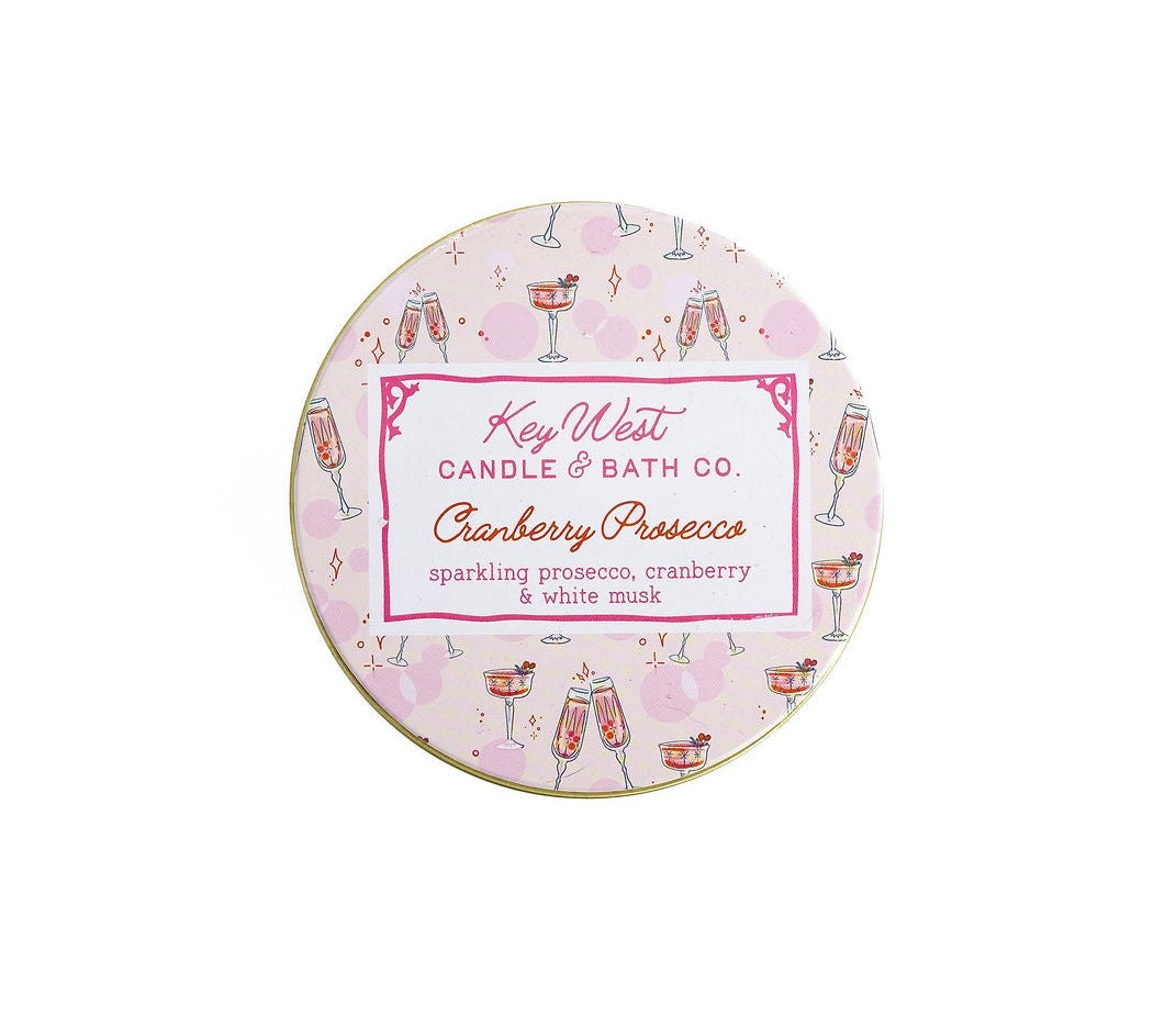 Round travel tin candle lid with Cranberry Prosecco label and drink illustrations
