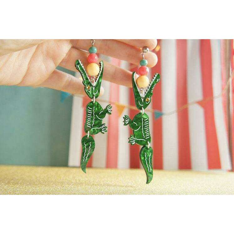 Laliblue crocodile earrings held up: green figures with red, yellow, and bead accents.