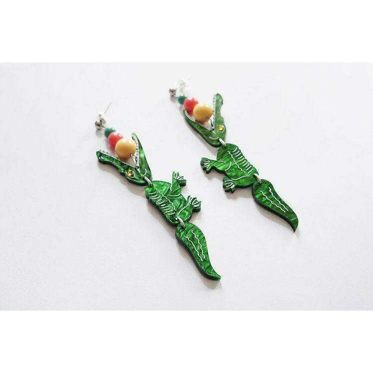 Laliblue crocodile earrings laid flat: green enamel bodies with red and beige bead details.