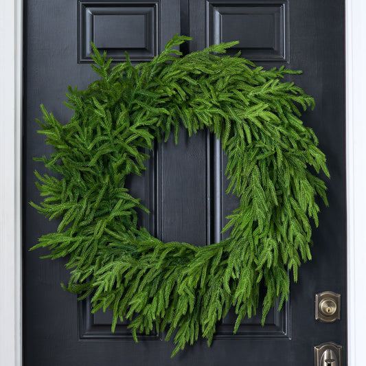 Green faux pine Christmas wreath mounted on a dark door.
