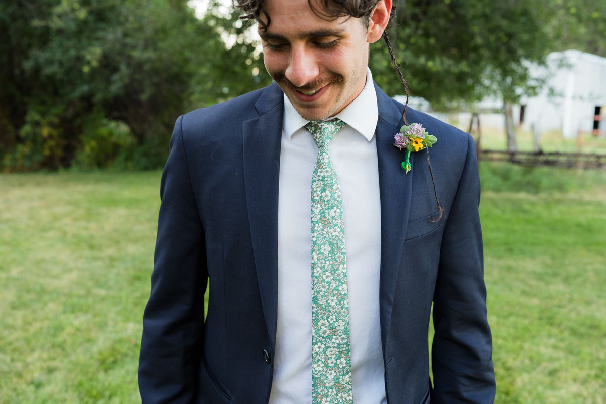 Men's floral tie on model, dark green with white and yellow blooms