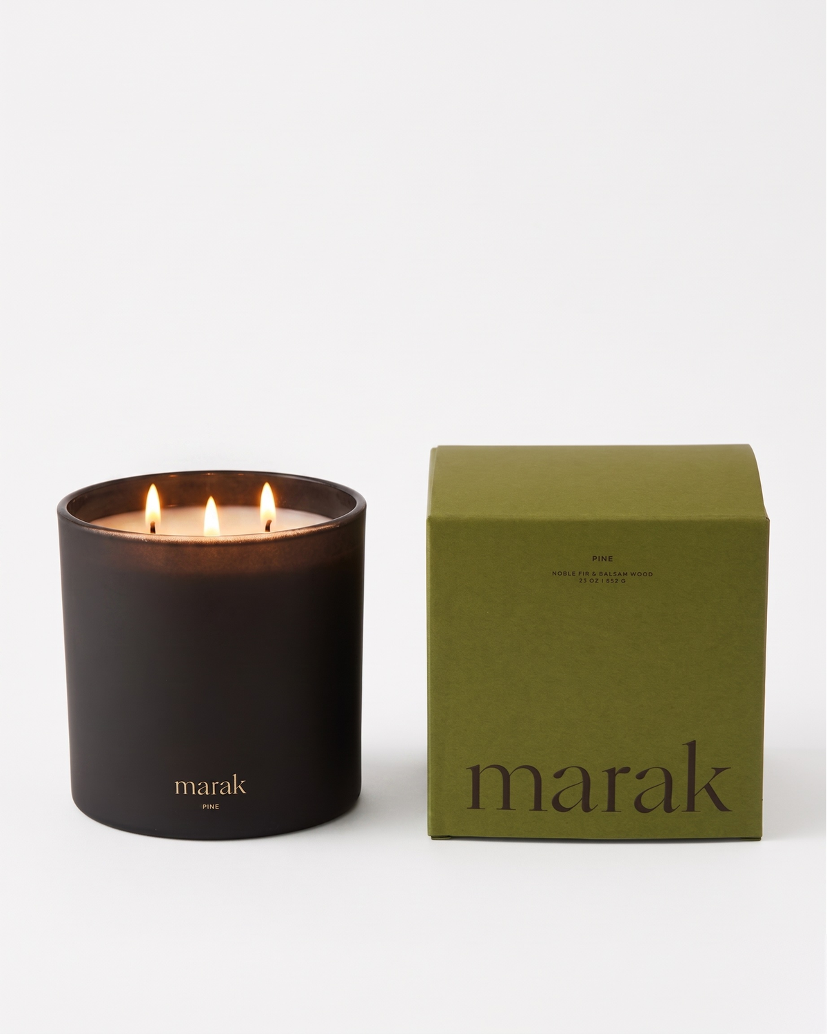 Black jar scented candle with flame beside green marak box
