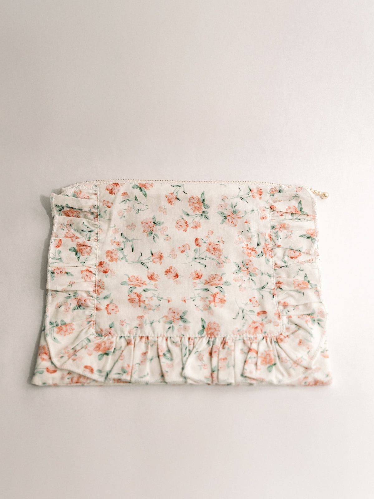 Floral ruffle zipper pouch with pastel flower print and gold zipper pull, front view