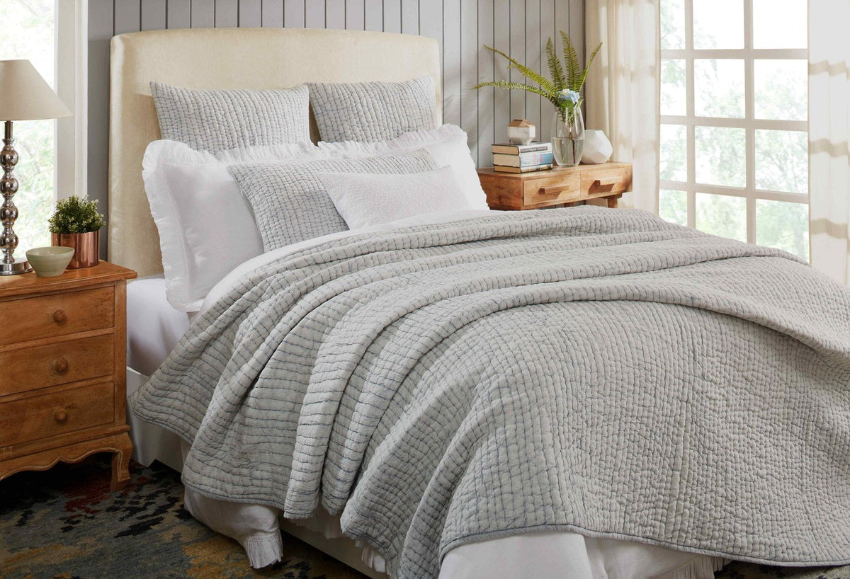 Gray stone-washed cotton quilt with stitched grid texture, layered on bed.