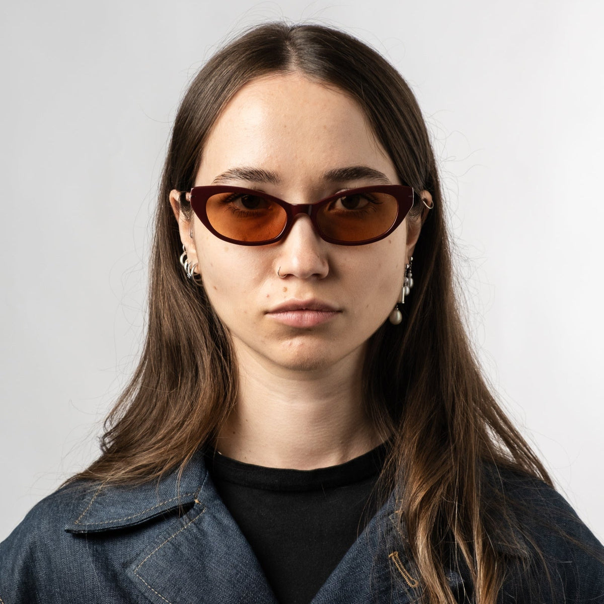 Model wearing burgundy cat-eye sunglasses with amber tinted lenses
