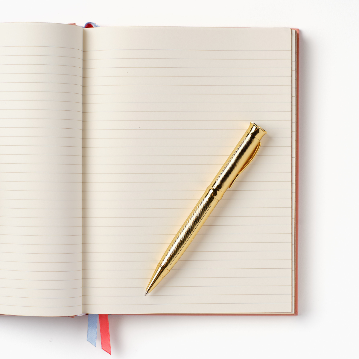 Hardcover notebook open with lined pages and a gold ballpoint pen