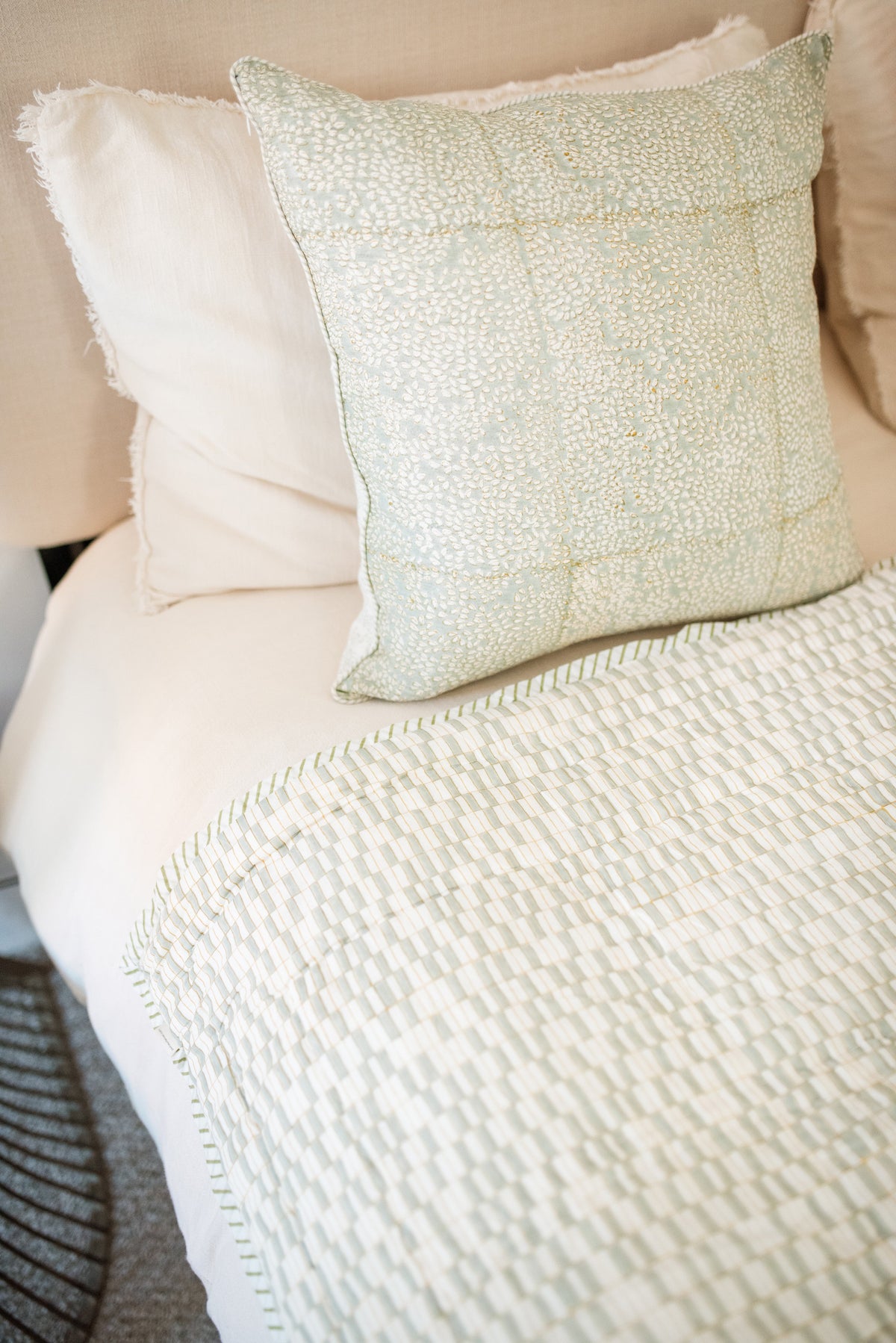 Pale green patchwork quilt with textured geometric pattern and matching pillow