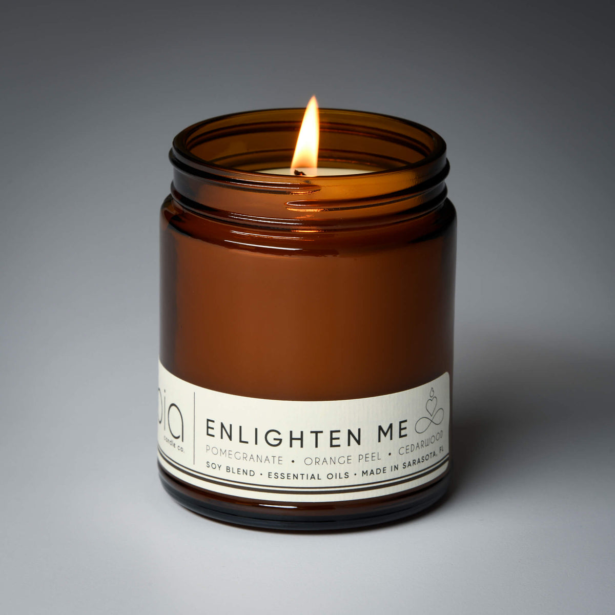 Amber glass jar soy candle with flame and white ENLIGHTEN ME label