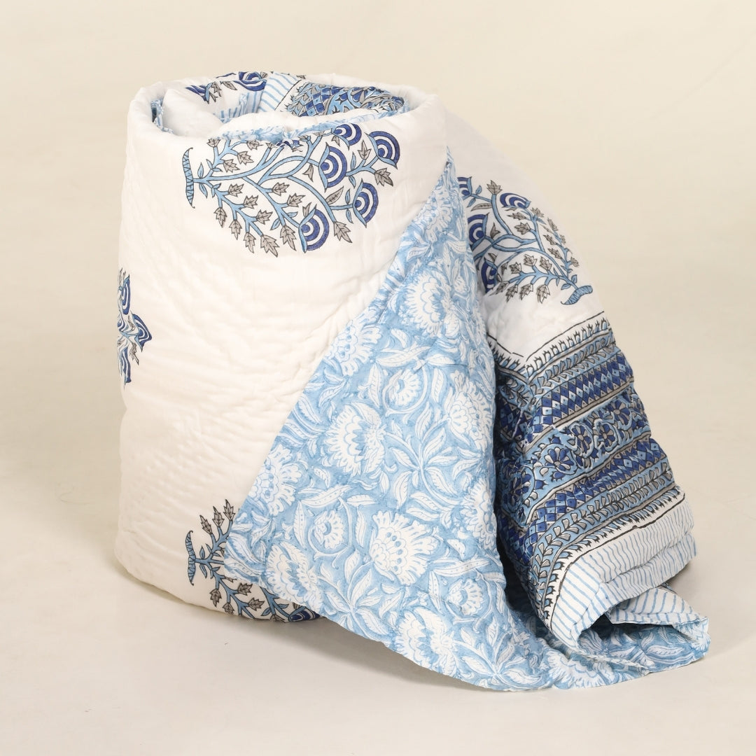 Folded reversible quilt with blue floral print and dark blue patterned border