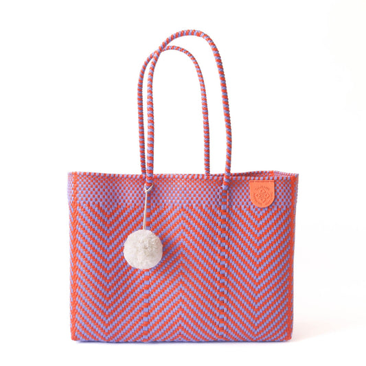 Woven tote bag with chevron zigzag pattern, rope handles, and pom-pom charm