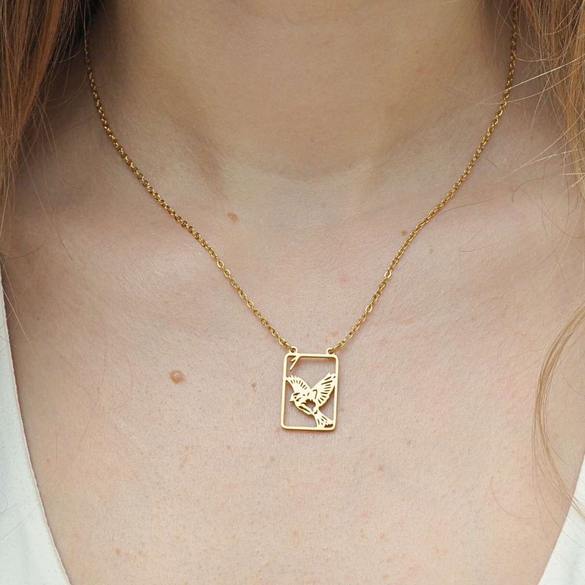 Gold necklace with small square sparrow pendant and fine chain