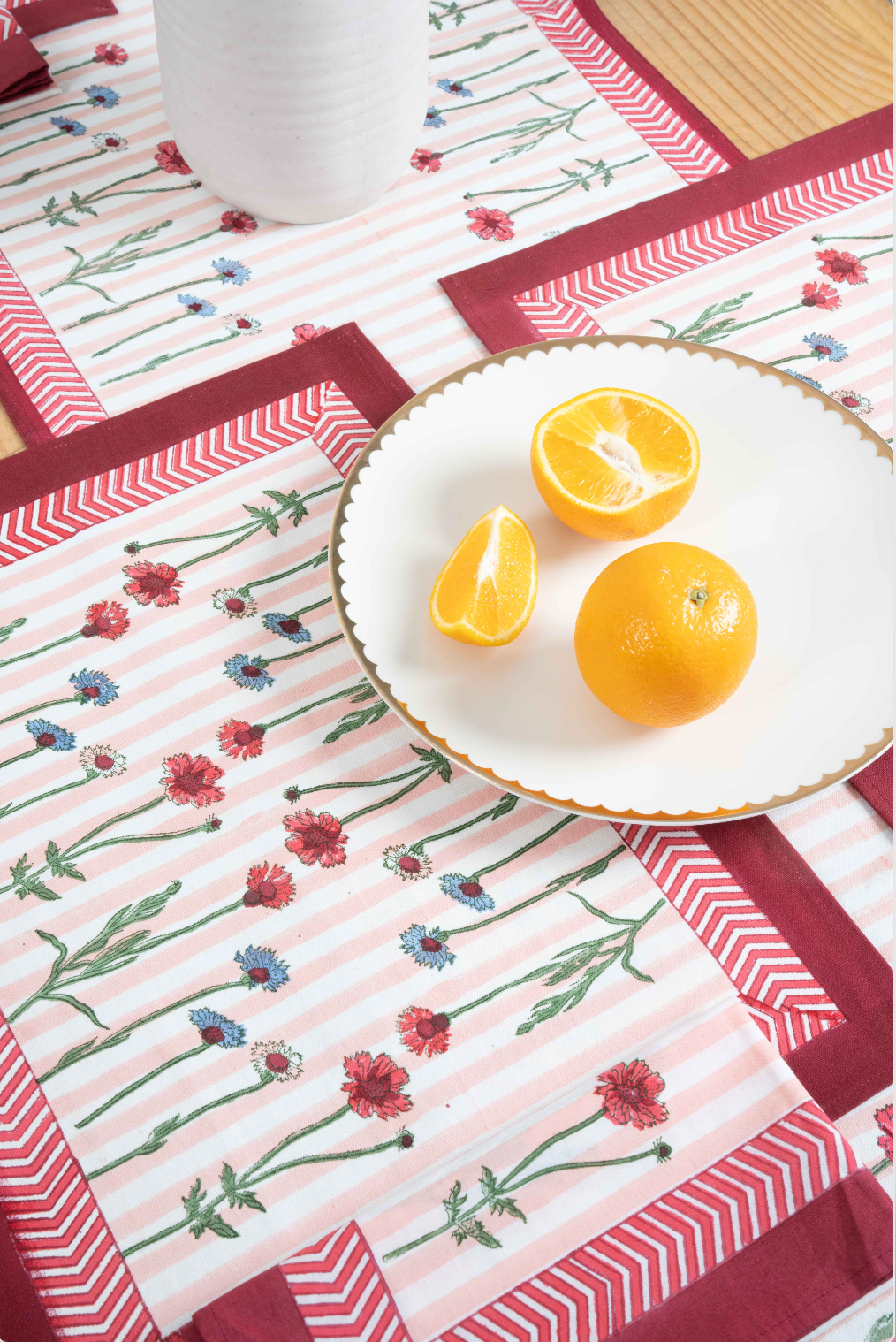 Set of 2 floral placemats with light pink field, red chevron border, blooming stems