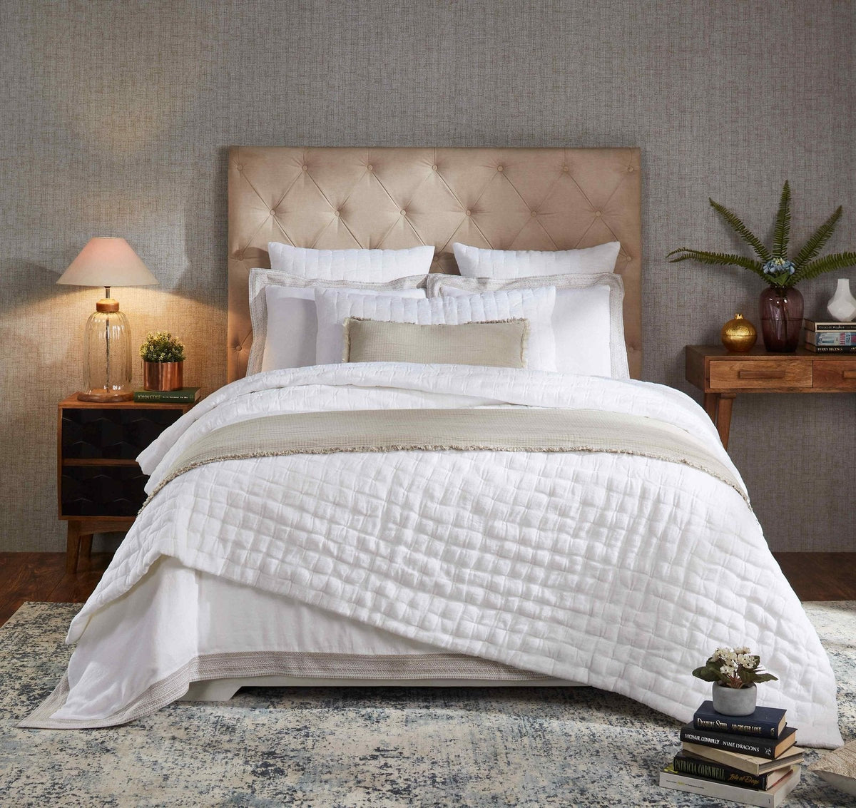 White pinched linen quilt with quilted stitch texture, neatly layered on a bed
