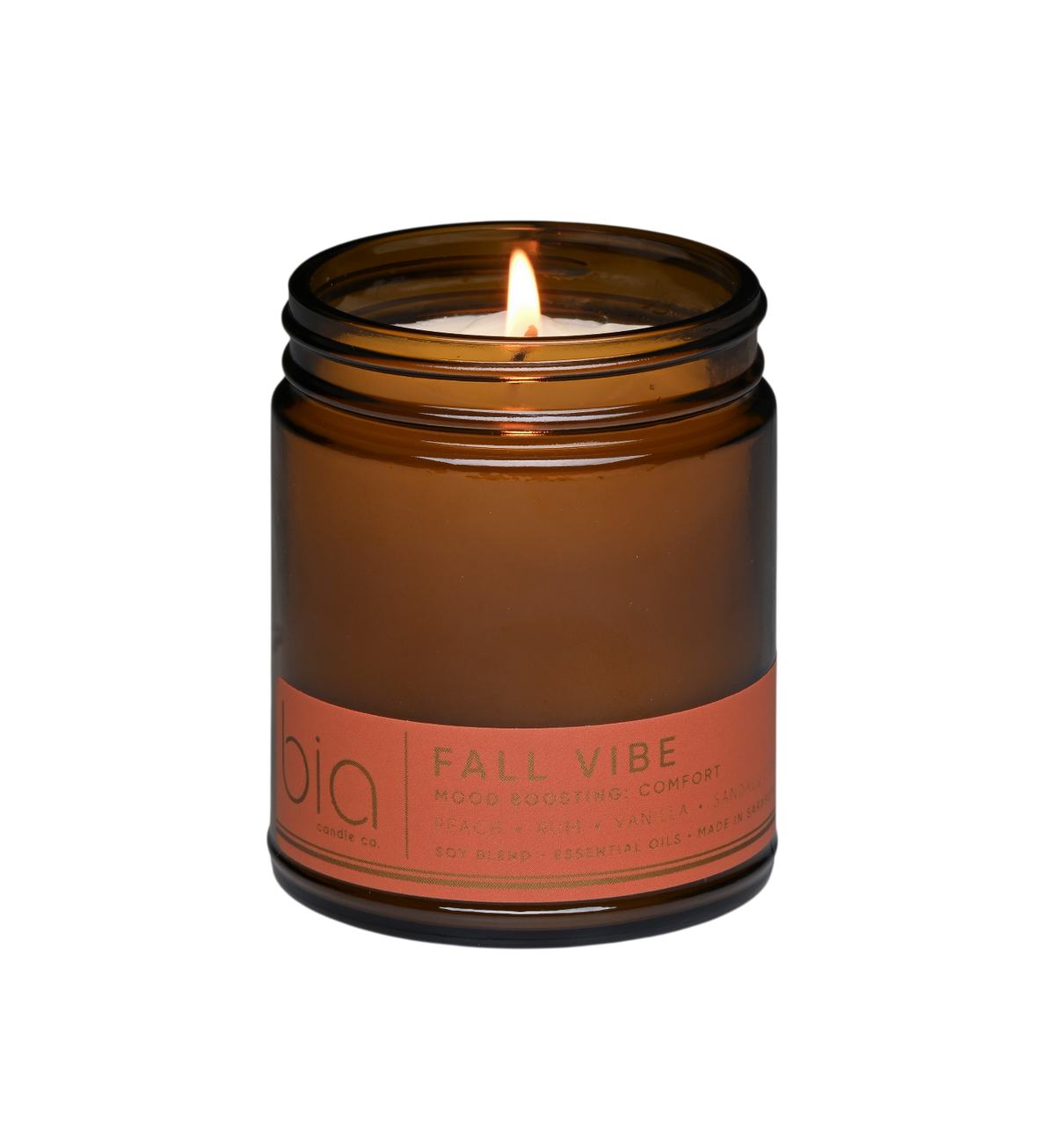 Amber soy candle in clear glass jar with lit wick and orange label band