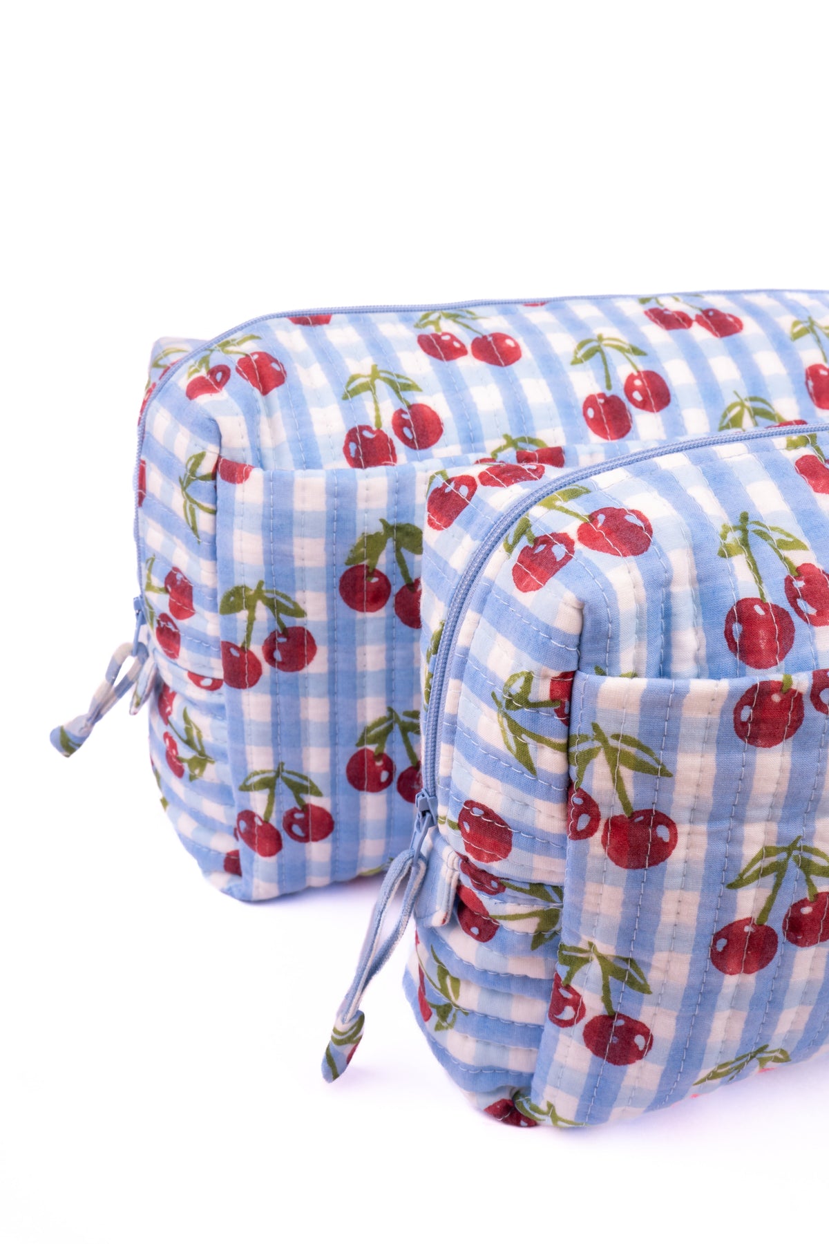 Cherry-print makeup bag on blue check fabric with tied side cords and zipper