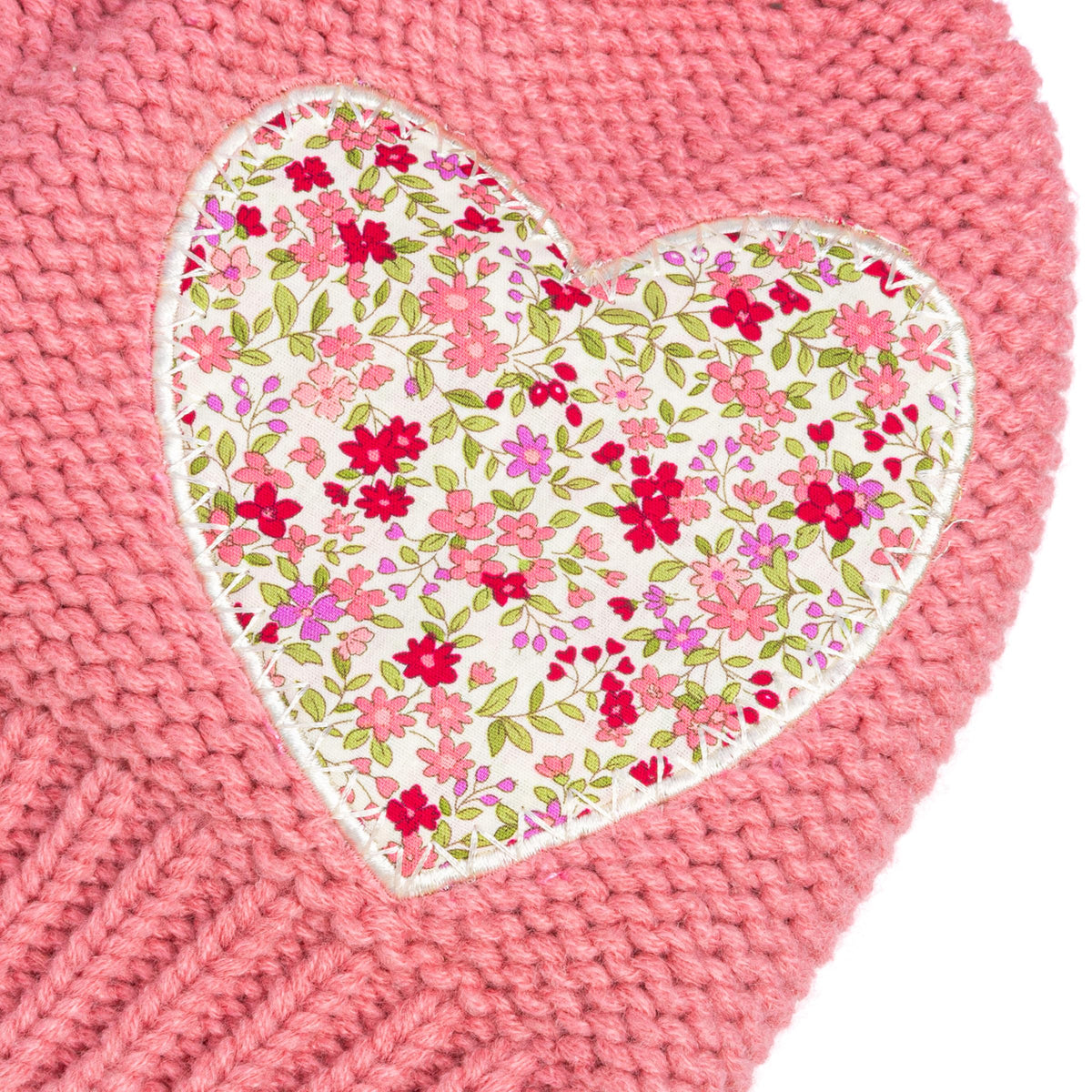 Close-up of floral heart applique stitched onto coral pink knit beanie