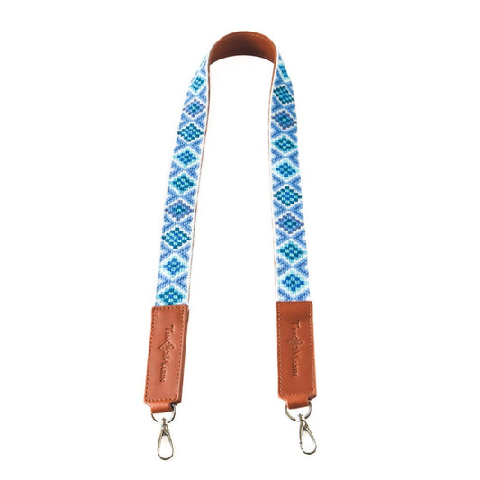 Woven bag strap with blue geometric pattern and tan leather end tabs, with metal hooks