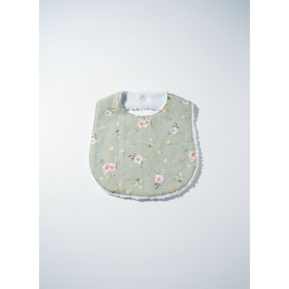 Floral sage green baby bib with light blue neck lining and stitched ruffled hem.