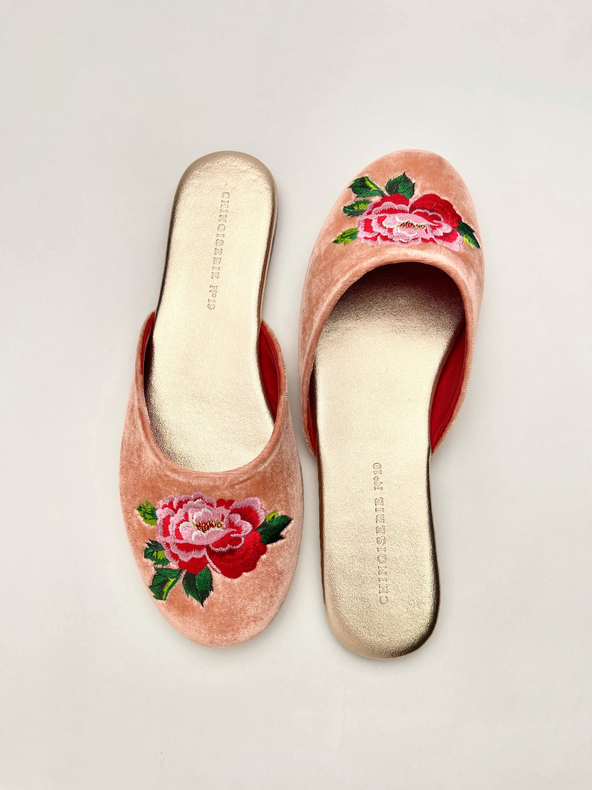 Peach velvet mules with peony embroidery on both shoes; side view