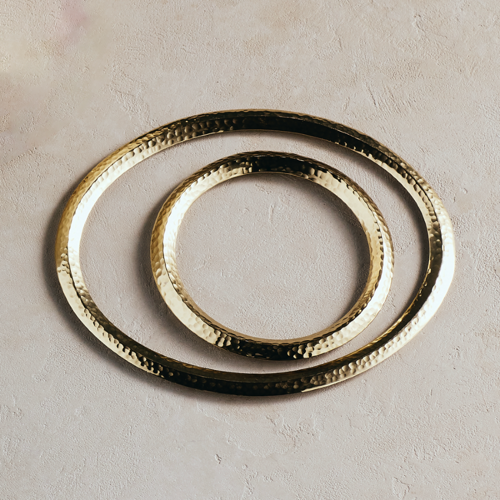 Set of 2 round metal trivets with hammered gold and dark ring detail.