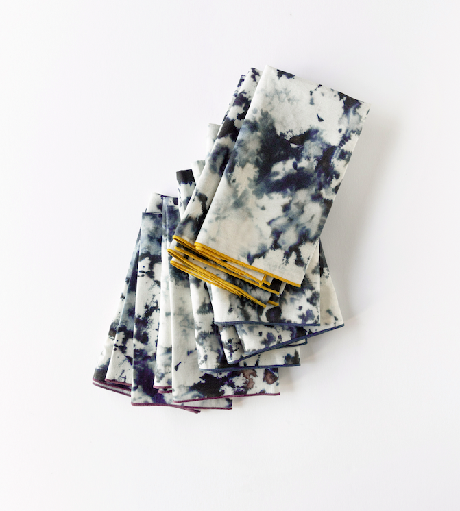 Stack of marble-print napkins with gold edging, white with dark blue-gray splatter