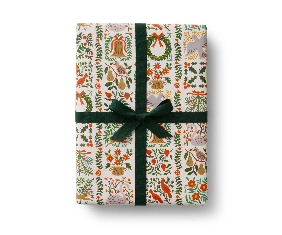 Christmas wrapping roll with holly, candy cane, and ornament pattern, tied with a green ribbon