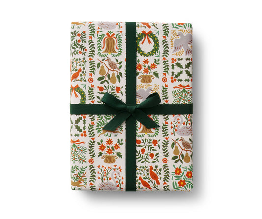 Christmas wrapping roll with holly, candy cane, and ornament pattern, tied with a green ribbon