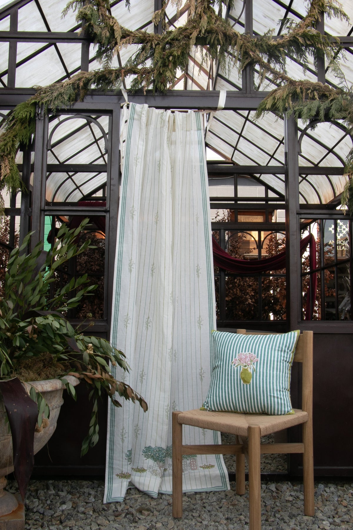 Green striped throw pillow with floral bouquet applique on a wooden chair