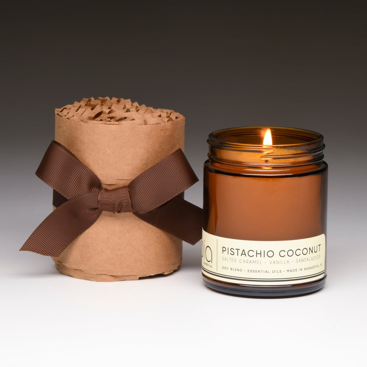 Wrapped gift candle set with ribbon, featuring one small lit amber jar