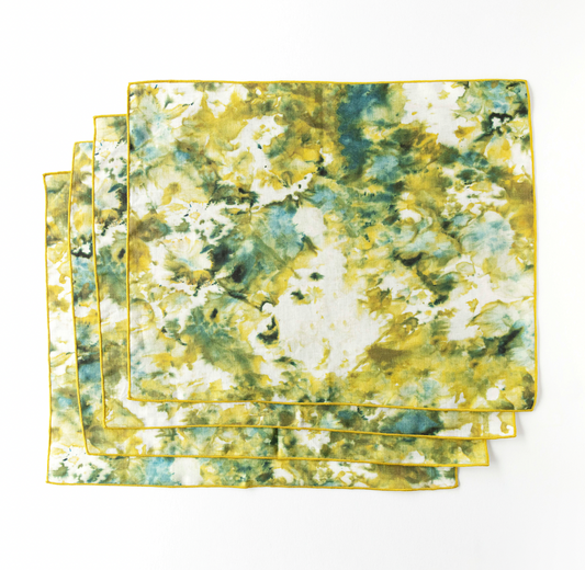 Stack of marble-look placemats in green and yellow with thin gold edge trim