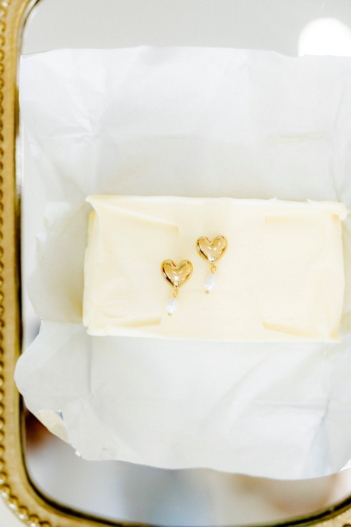 Gold-tone heart dangle earrings with pearl drops on tissue-lined box.