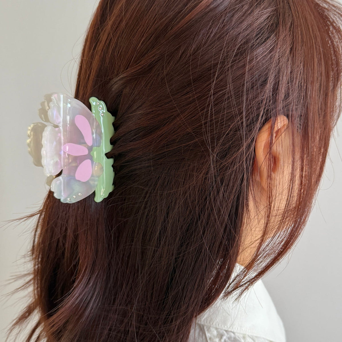 Orchid flower hair claw clipped in brown hair, translucent white petals and green teeth