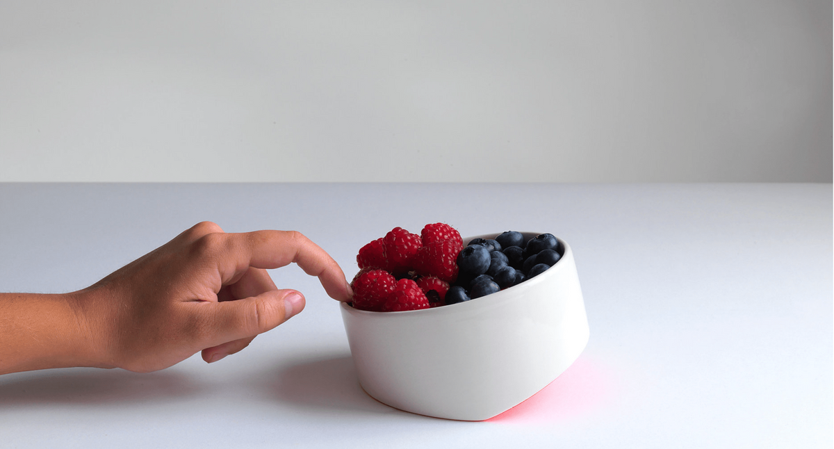 Ceramic bowl filled with fresh berries, held by hand
