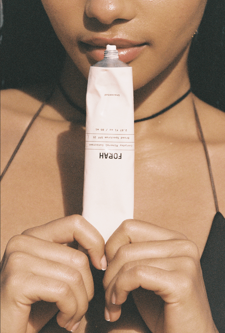 Mineral sunscreen squeeze tube with product dispensed; applying to skin