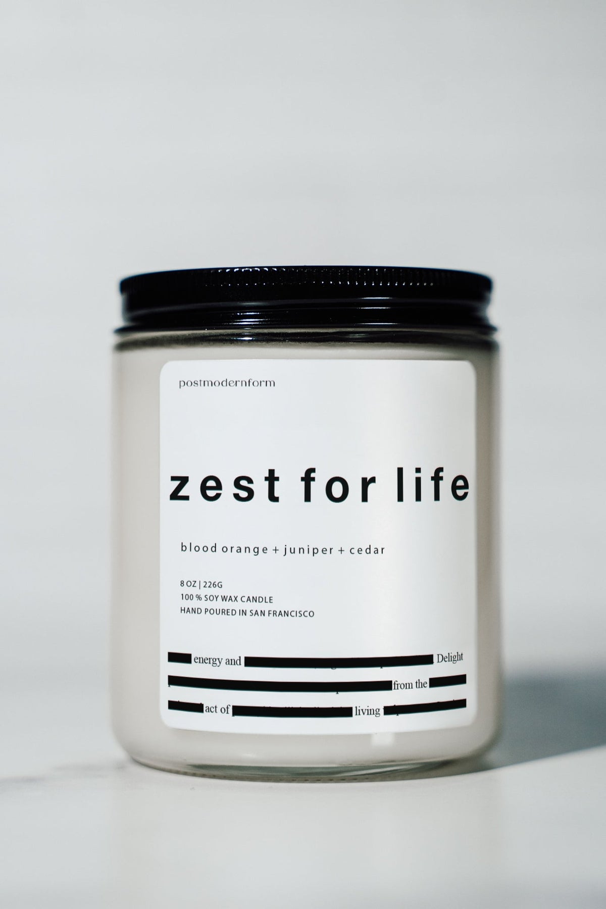 Zest for life candle jar with black lid and white label, front view