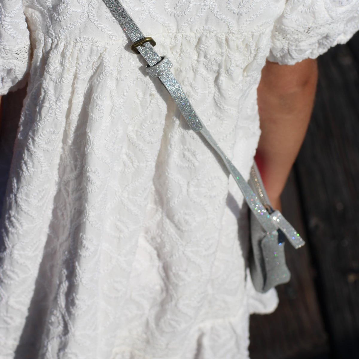 Silver glitter crossbody strap with sparkly buckle and metal attachment