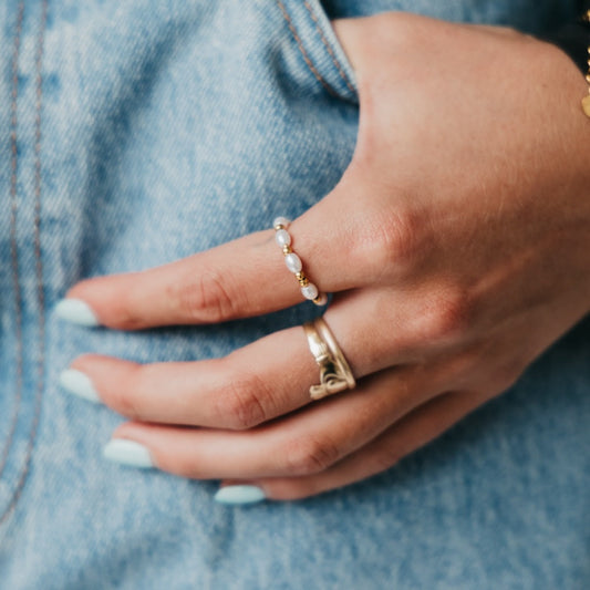 Gold-and-pearl beaded bracelet on wrist with denim sleeve
