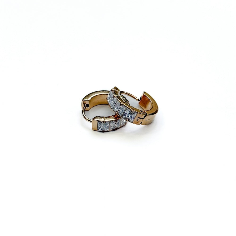 Gold huggie hoop earrings with diamond-like stones and hinged clasp detail