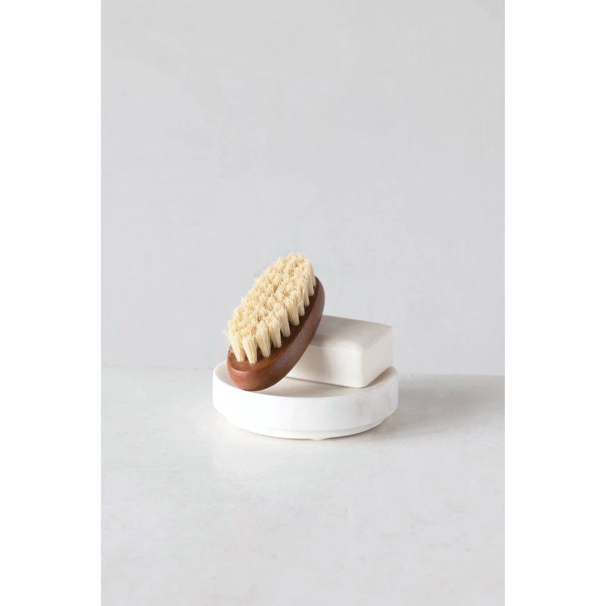 Round white marble soap dish with wooden brush and bristles