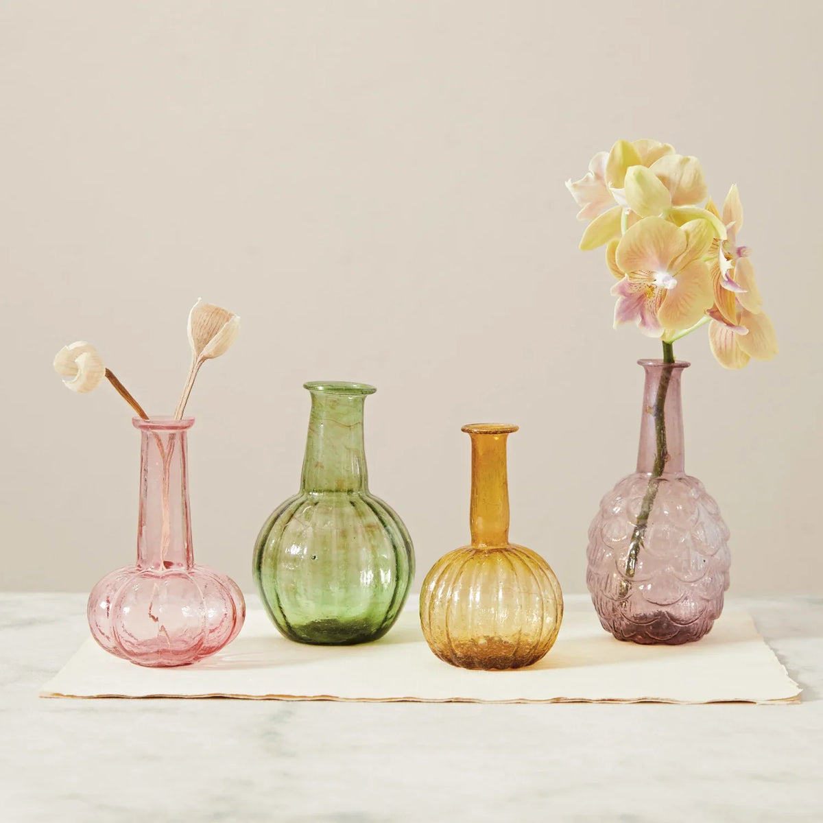 Set of four hand-blown glass vases: pink, green, amber, and lavender with flowers