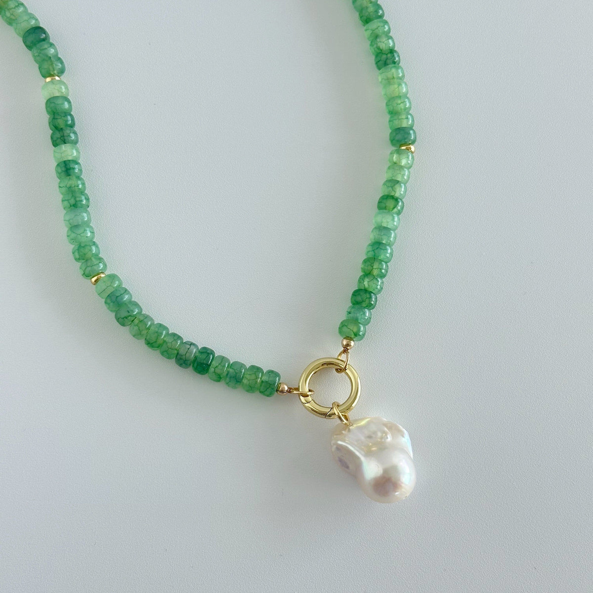 Green bead necklace with gold ring clasp and irregular pearl drop charm