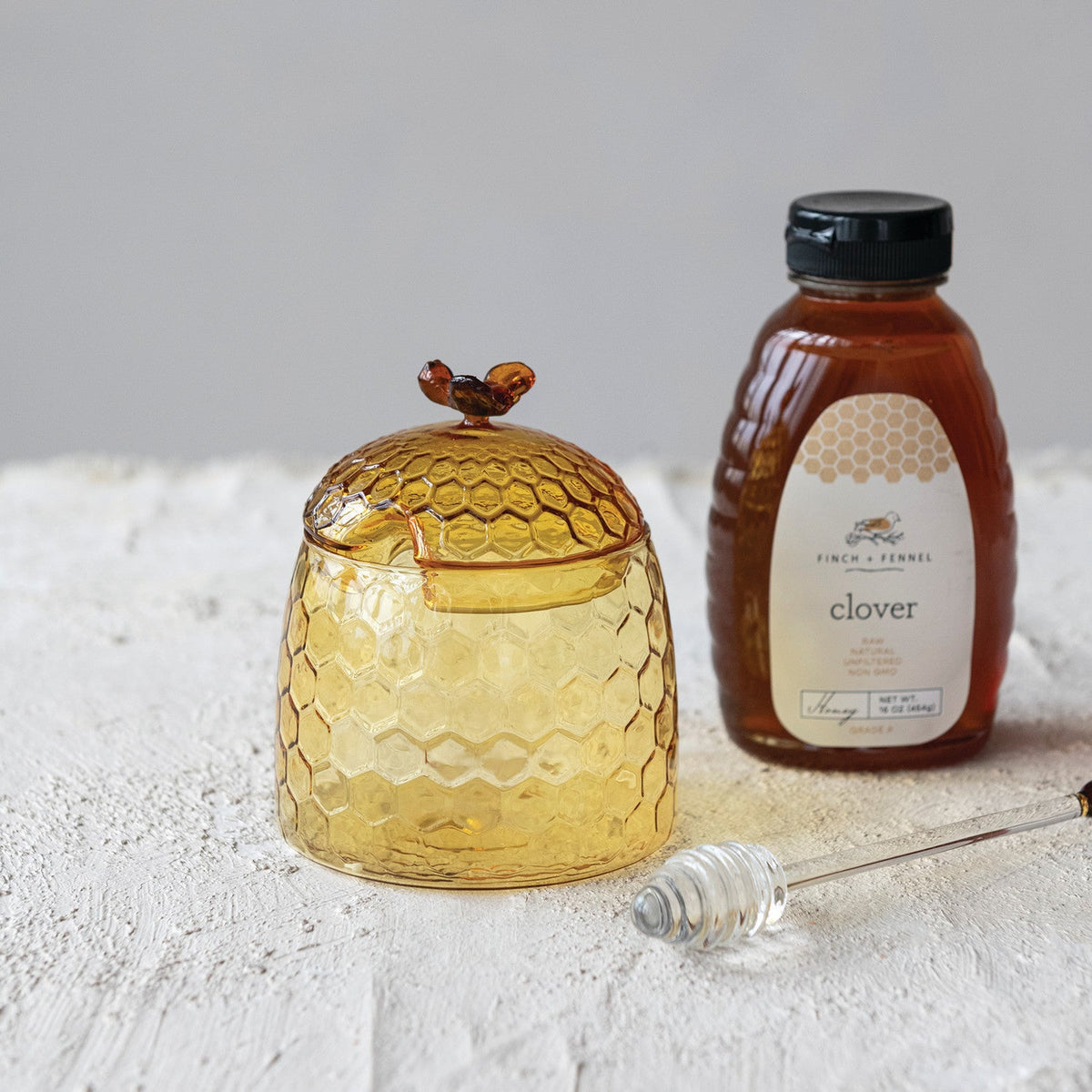 Glass honey jar with bee finial and matching honey dipper, amber-gold