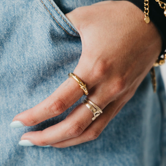 Gold tone diamond-studded ring on finger, close-up