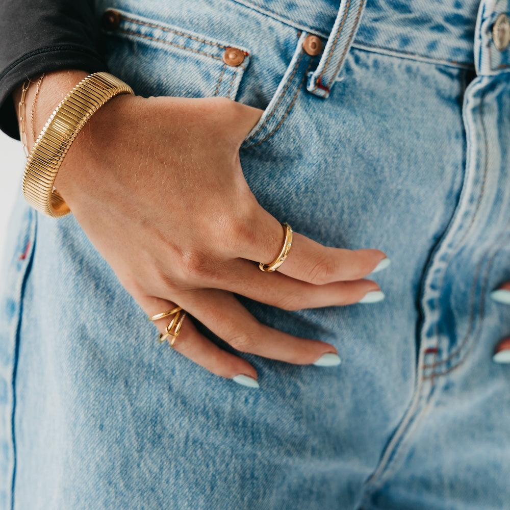 Gold tone diamond-studded ring worn on hand with another band
