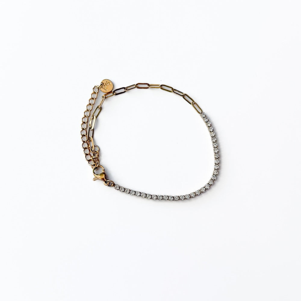 Gold-tone tennis bracelet with clear rhinestone band and small round logo charm