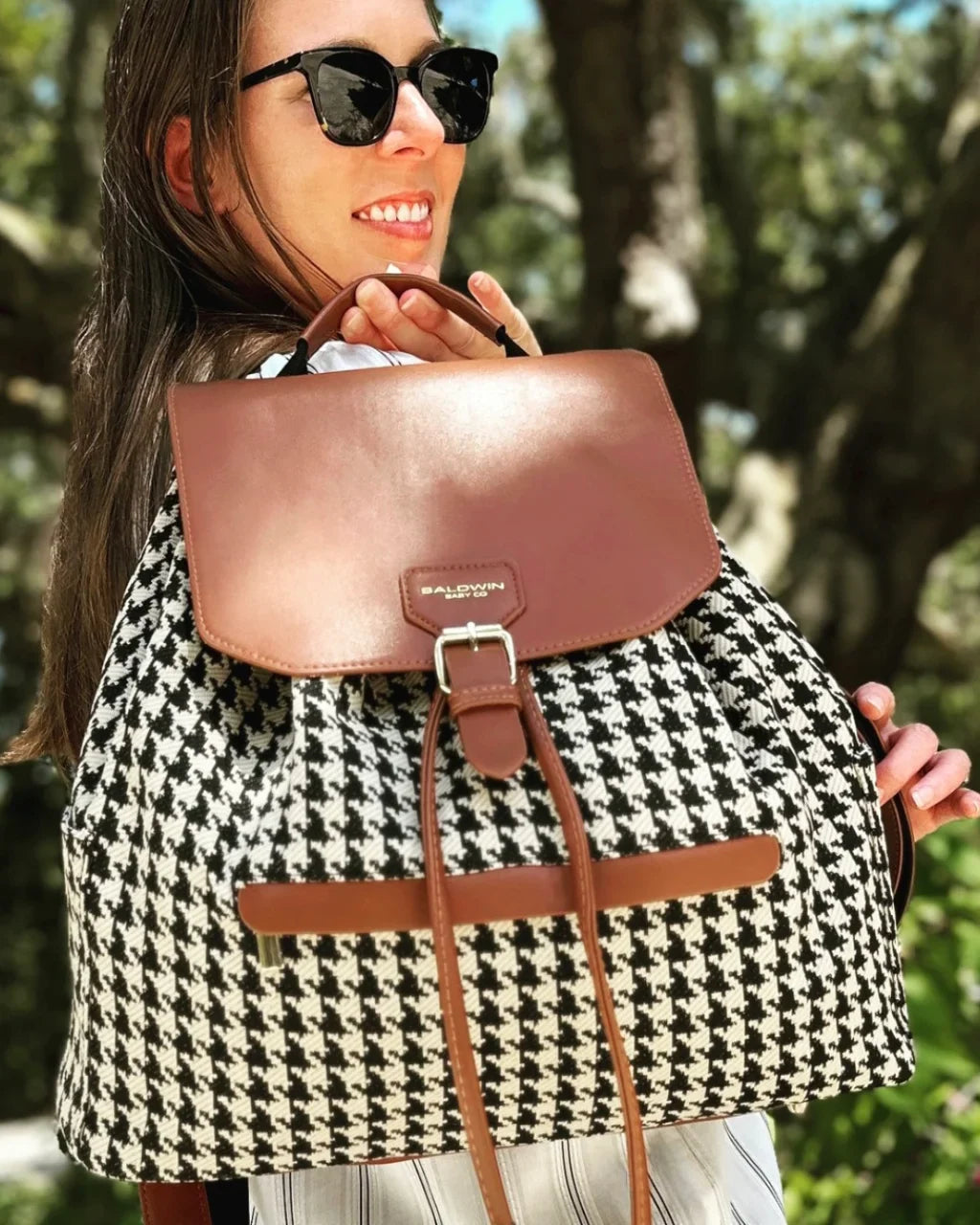 Houndstooth diaper bag with brown flap and trim, carried by its top handle
