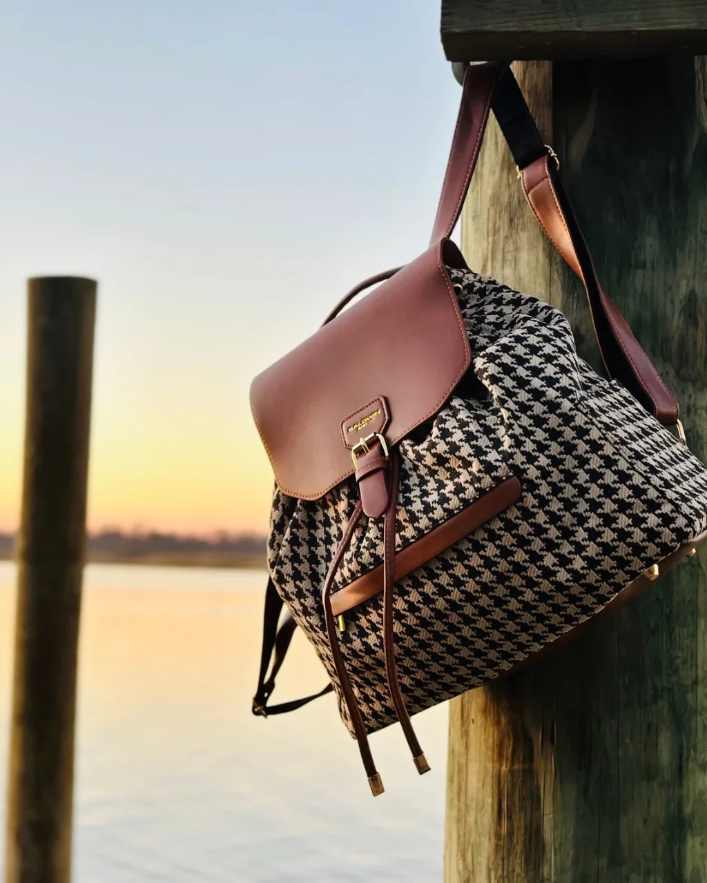 Side view of houndstooth diaper bag with brown flap, drawstring, and shoulder straps