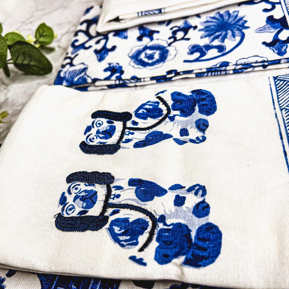 Chinoiserie tea towel close-up with blue dog and floral motifs on white